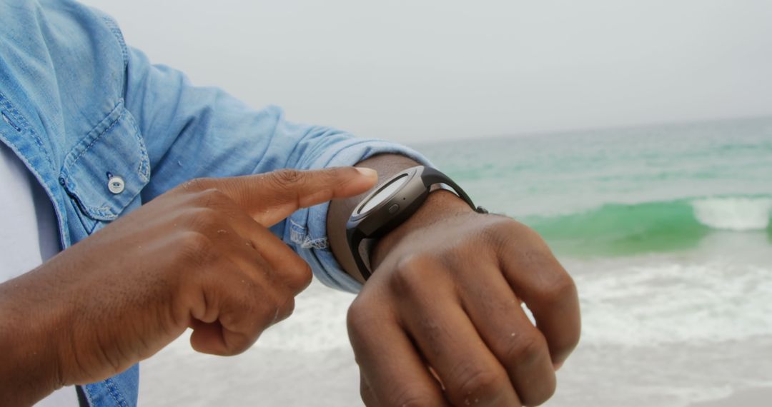 Man Interacting with Smartwatch by Ocean