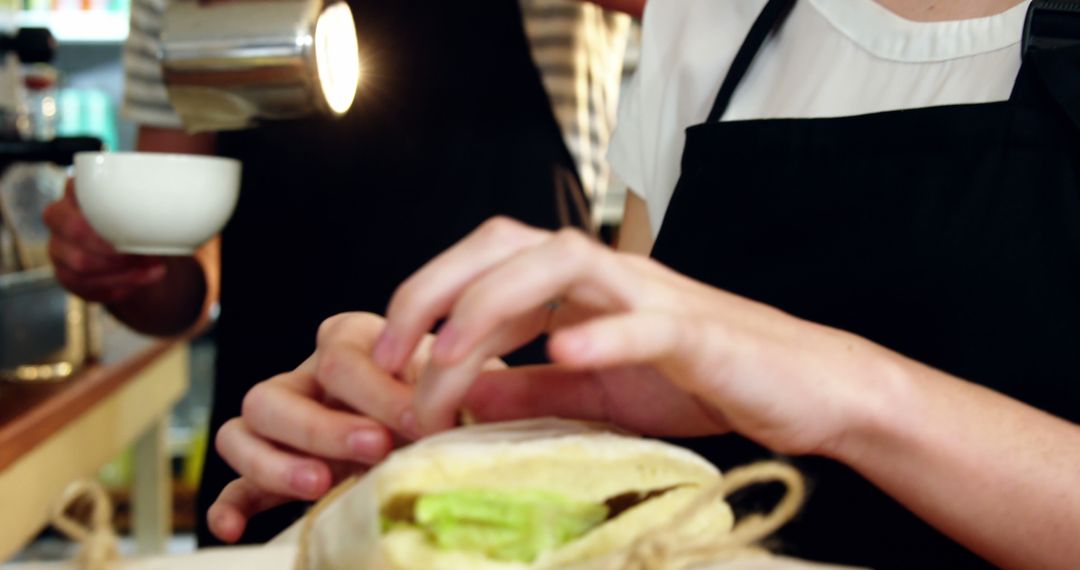 Hands Preparing Sandwich at Café Counter Under Lamp Light - Free Images, Stock Photos and Pictures on Pikwizard.com