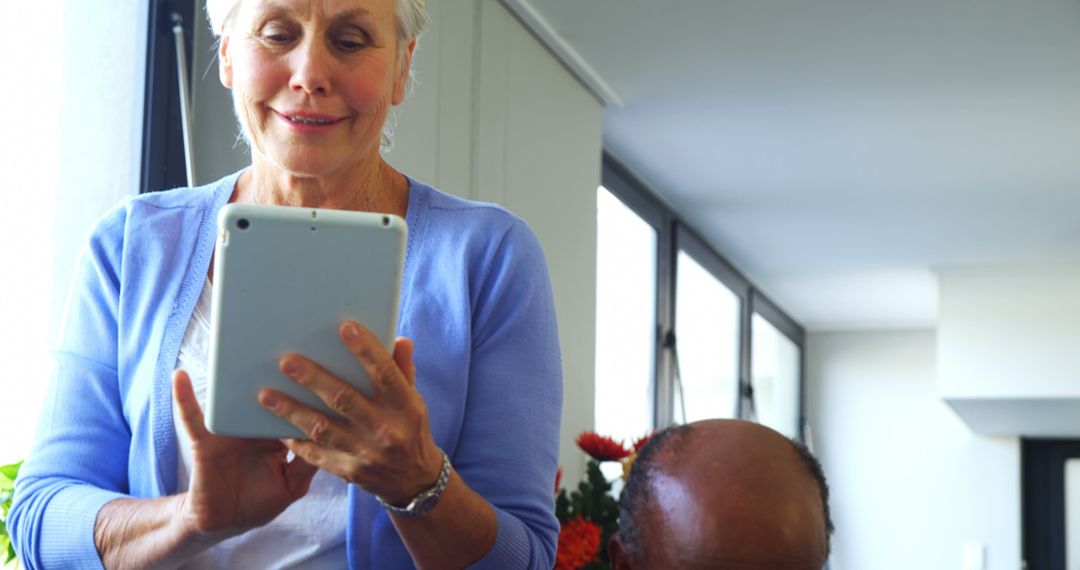 Smiling Senior Woman Using Tablet in Bright Living Room - Free Images, Stock Photos and Pictures on Pikwizard.com