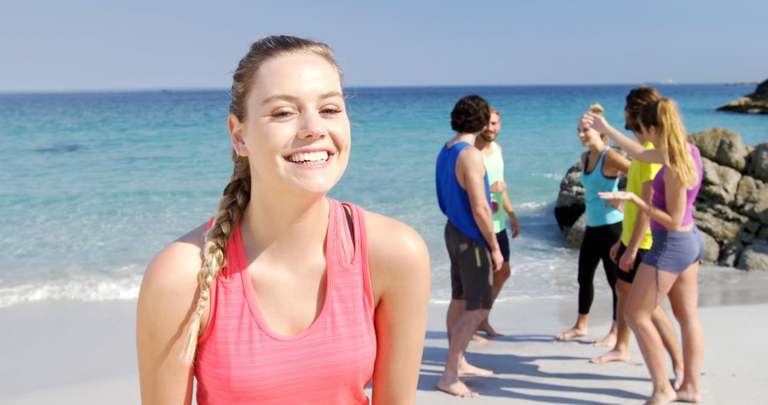 Cheerful Young Woman Enjoying Beach with Friends in Background - Free Images, Stock Photos and Pictures on Pikwizard.com