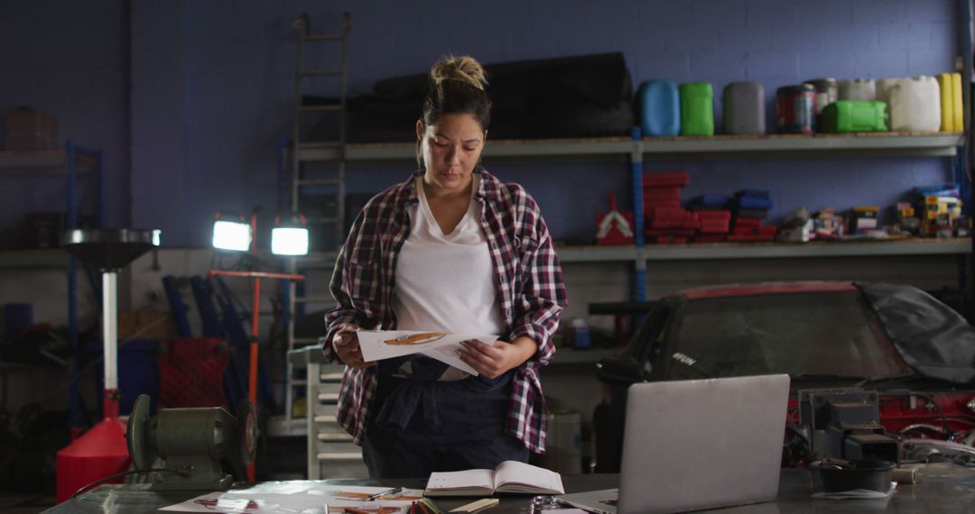 Female auto mechanic reviewing documents in industrial garage - Free Images, Stock Photos and Pictures on Pikwizard.com