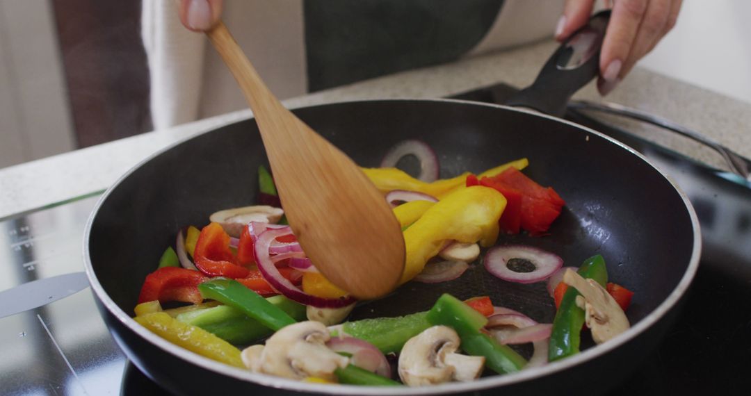 Person Stirring Vegetables in Frying Pan on Induction Stove - Free Images, Stock Photos and Pictures on Pikwizard.com