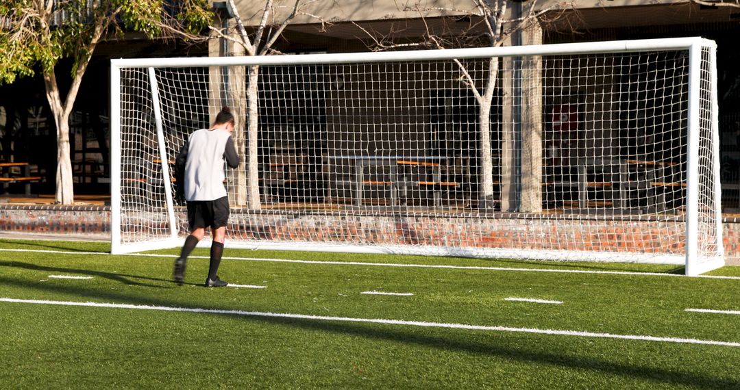 Young Soccer Player Walking Towards Goal Post, Daytime Field Play