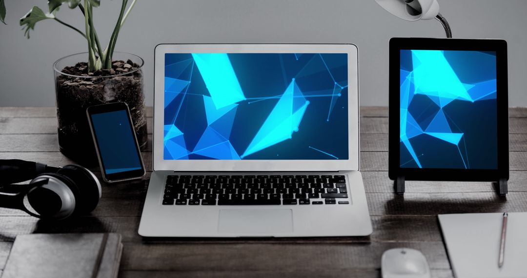 Modern Workspace with Laptop, Tablet and Phone Displaying Blue Abstract Graphics