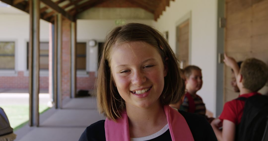 Smiling Schoolgirl in Corridor with Classmates in Background