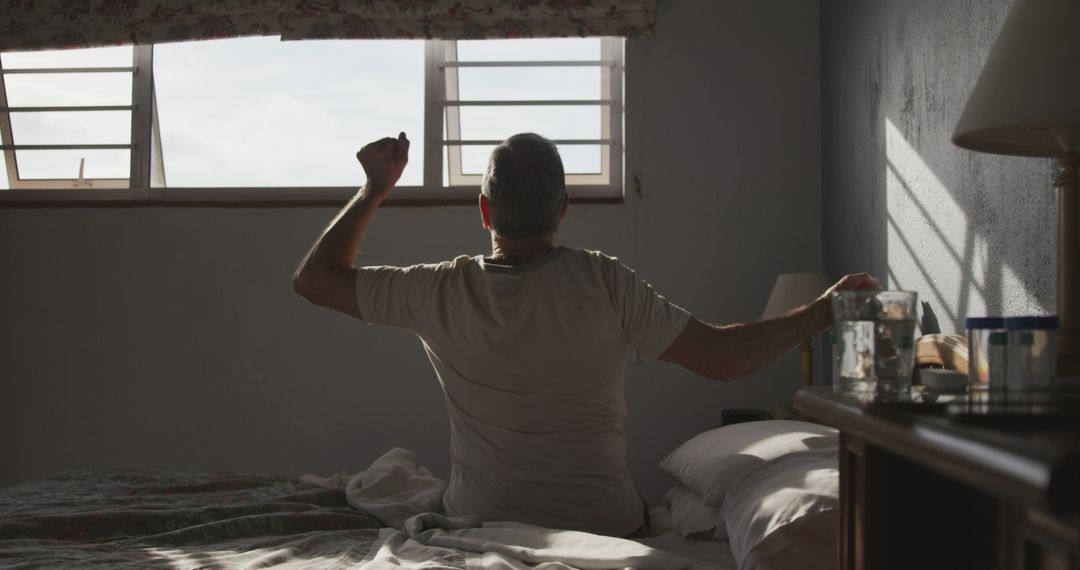 Man stretching in bed during sunrise at home - Free Images, Stock Photos and Pictures on Pikwizard.com