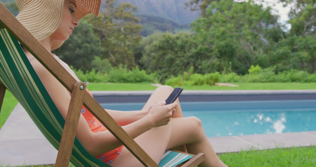 Young Woman in Sun Hat Relaxing by Poolside with Smartphone - Free Images, Stock Photos and Pictures on Pikwizard.com