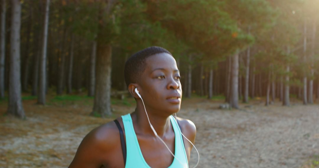 Focused African American Woman Jogging in Forest Wearing Earphones - Free Images, Stock Photos and Pictures on Pikwizard.com