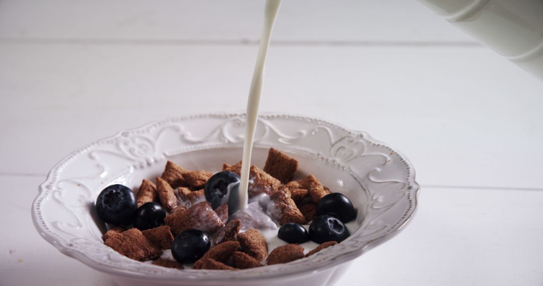 Pouring Milk into Cereal Bowl with Blueberries for Breakfast - Free Images, Stock Photos and Pictures on Pikwizard.com