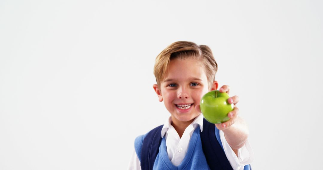 Smiling Schoolboy Holding Green Apple Against White Background - Free Images, Stock Photos and Pictures on Pikwizard.com