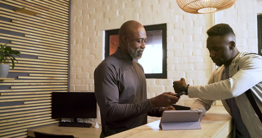 Client Scanning Smartwatch for Entry at Modern Gym Reception