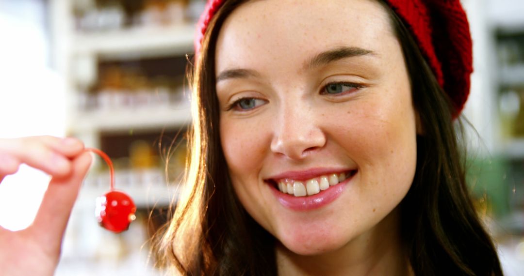 Smiling Woman Holding Red Cherry While Wearing Red Hat - Free Images, Stock Photos and Pictures on Pikwizard.com