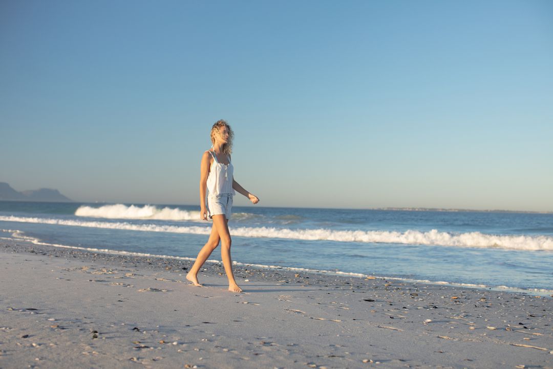 Woman walking barefoot on the beach - Free Images, Stock Photos and Pictures on Pikwizard.com