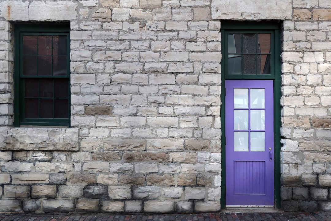 Purple Door with Green Frame on Rustic Stone Wall