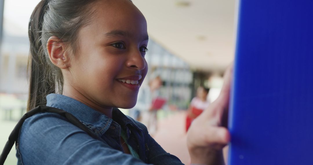 Smiling Biracial Schoolgirl at Locker in School Corridor