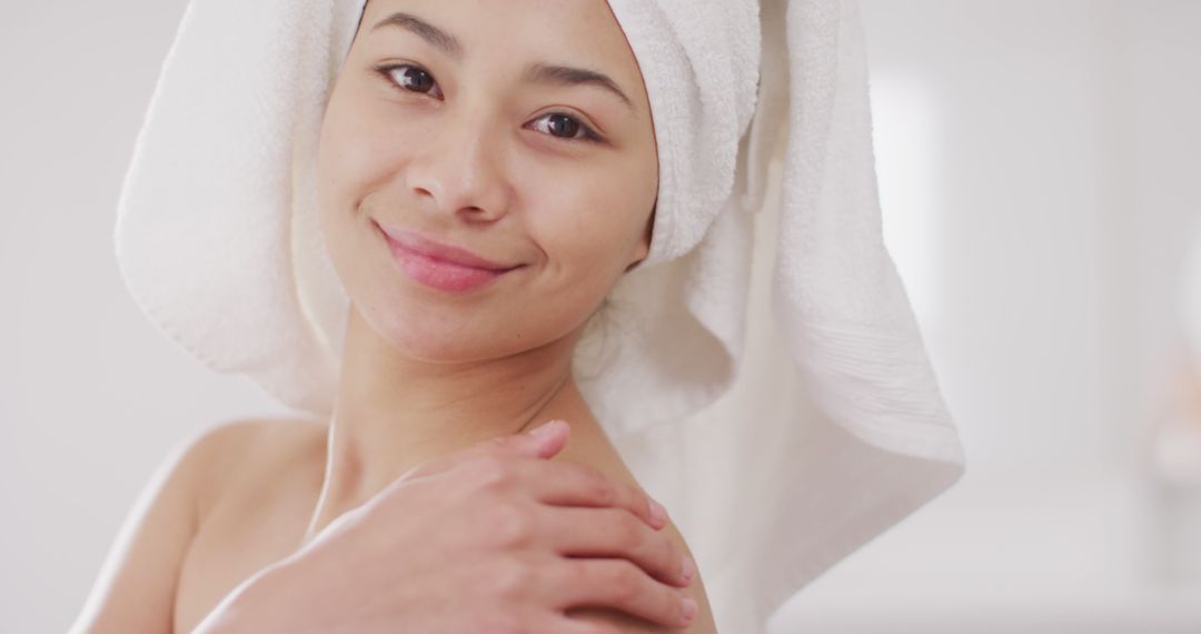 Image of portrait of smiling biracial woman with towel on hair in bathroom - Free Images, Stock Photos and Pictures on Pikwizard.com