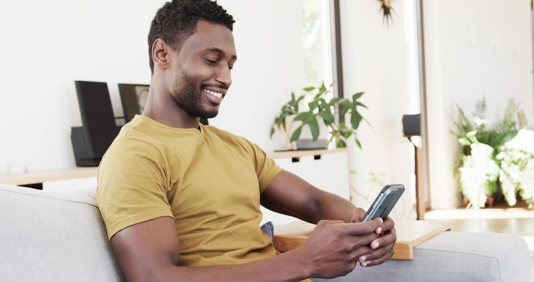 Smiling Man Checking Smartphone in Modern Living Room - Free Images, Stock Photos and Pictures on Pikwizard.com