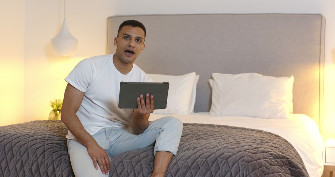 Man Video Calling While Sitting on a Bed with Tablet