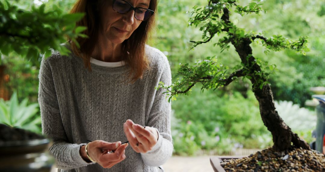 Woman Taking Care of Bonsai Tree in Outdoor Garden - Free Images, Stock Photos and Pictures on Pikwizard.com