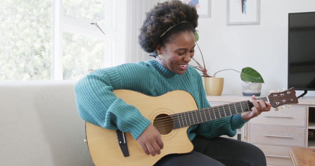 Smiling Young Woman Playing Acoustic Guitar Indoors - Free Images, Stock Photos and Pictures on Pikwizard.com