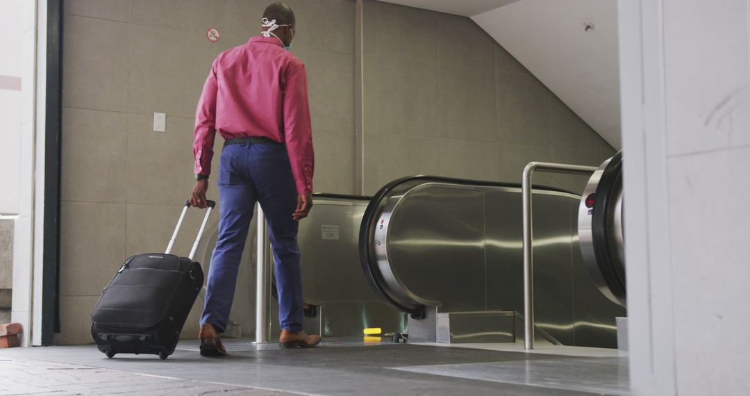 Rear View of Businessman with Suitcase Heading Down Escalator at Airport - Free Images, Stock Photos and Pictures on Pikwizard.com