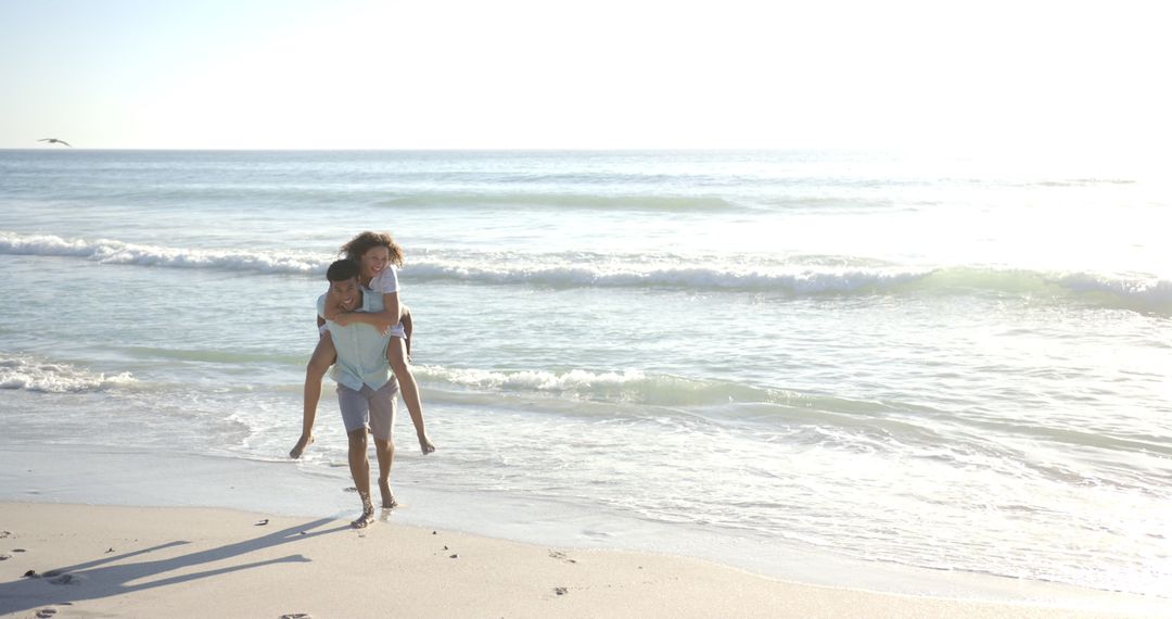 Couple Enjoying Romantic Beach Stroll at Sunset with Piggyback Ride