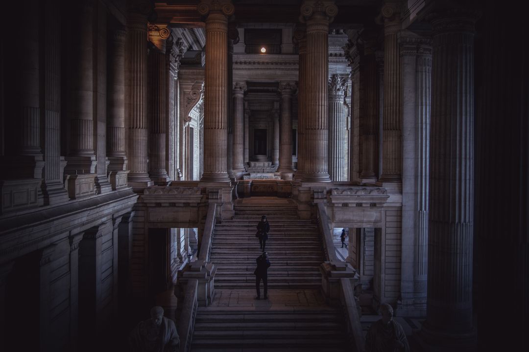 Dimly Lit Grand Hall with Majestic Columns and Stairs