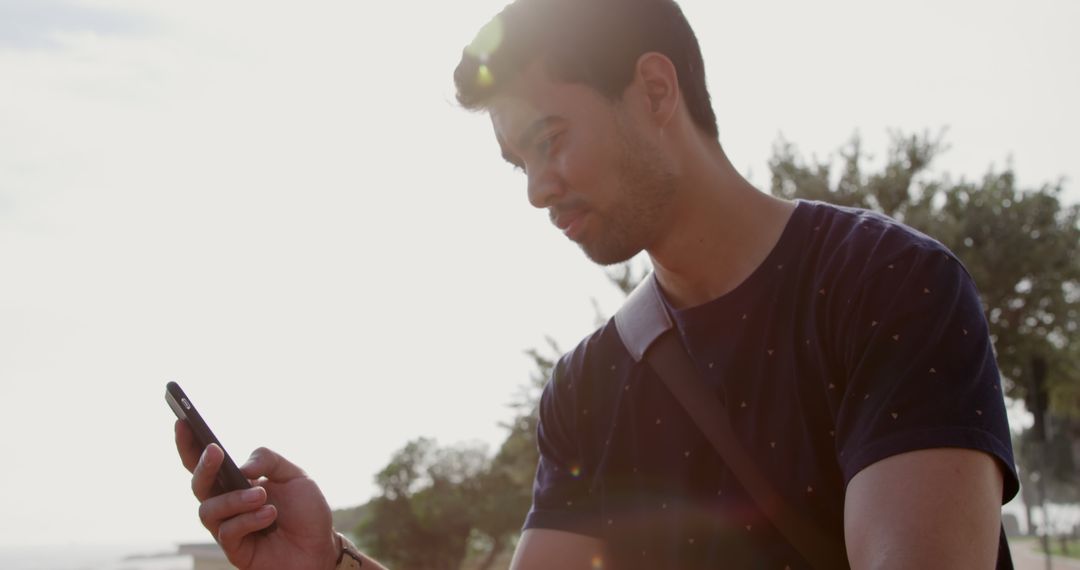 Man Relaxing Outdoors Using Smartphone in Sunshine