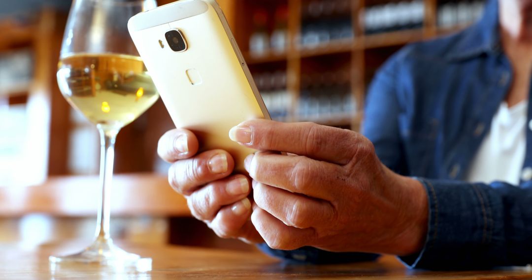 Middle-Aged Enjoying Wine While Checking Smartphone at Cozy Bar