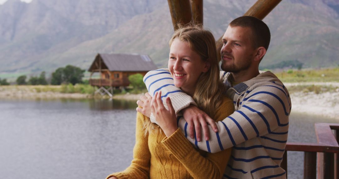 Couple Embracing on Riverside Log Cabin Terrace for Tranquil Getaway