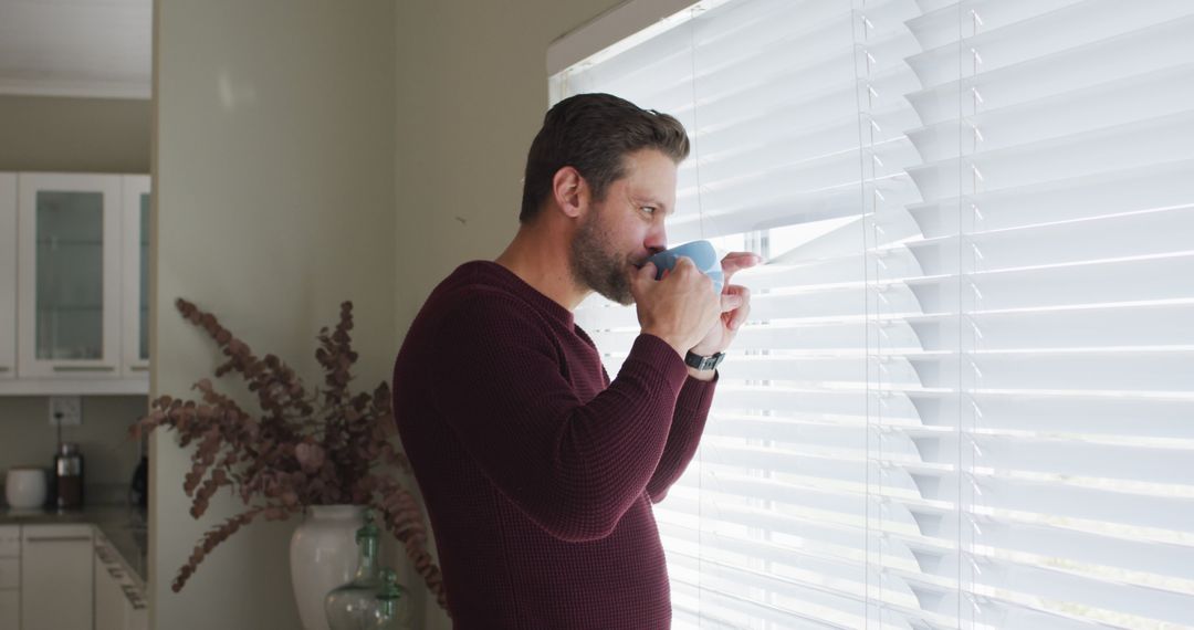 Image of thoughtful caucasian man drinking coffee and looking outside window - Free Images, Stock Photos and Pictures on Pikwizard.com