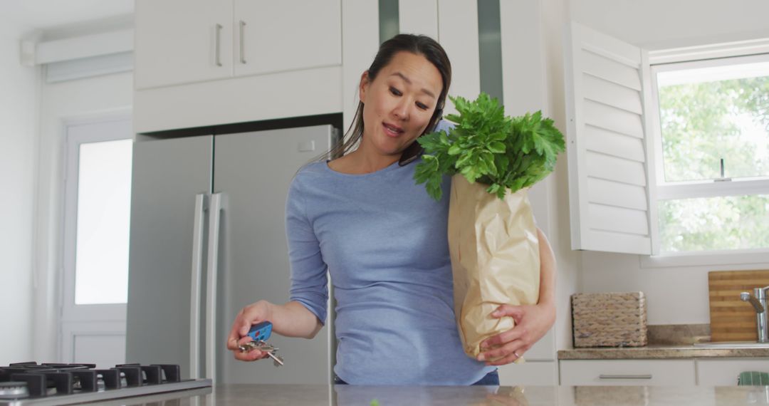 Woman Holding Groceries While Talking On Phone In Kitchen - Free Images, Stock Photos and Pictures on Pikwizard.com