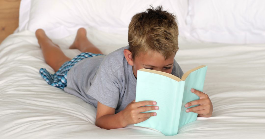 Young Boy Reading Book on Bed - Free Images, Stock Photos and Pictures on Pikwizard.com