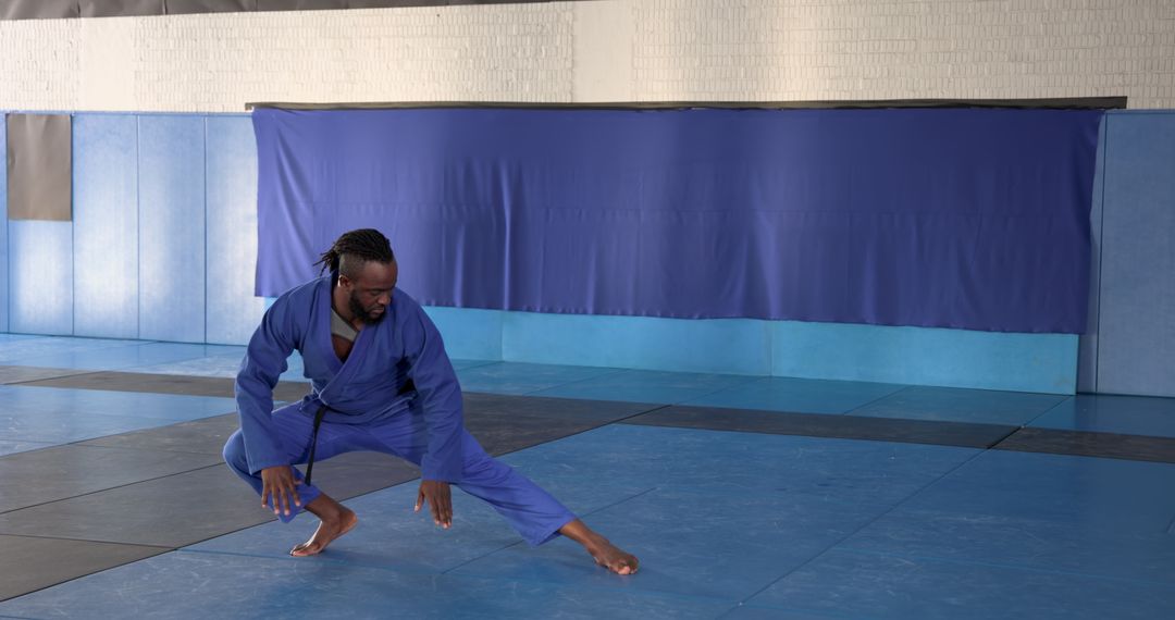 Martial Artist Displaying Precision in Blue Gi on Dojo Mat