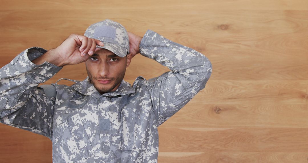 Army Soldier Adjusting Cap in Camouflage Uniform - Free Images, Stock Photos and Pictures on Pikwizard.com