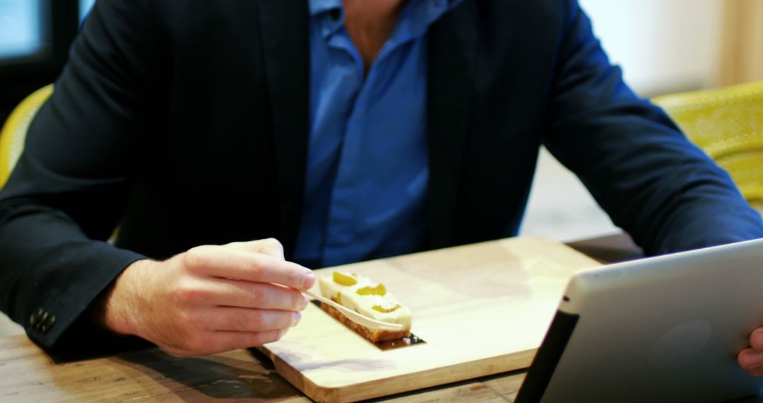 Business Professional Multitasking in Cafe with Tablet and Pastry