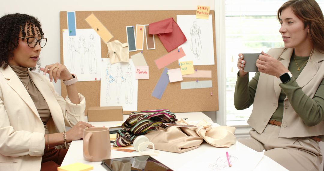 Fashion designers collaborating over fabric swatches and moodboard in creative studio