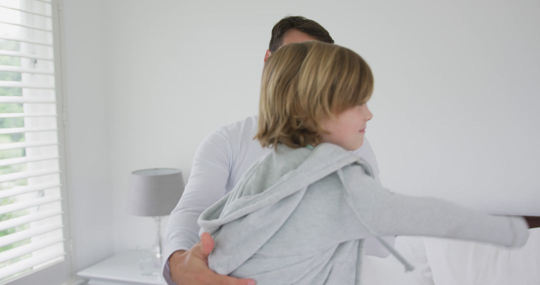 Father Holding Young Son in Bright White Bedroom - Free Images, Stock Photos and Pictures on Pikwizard.com