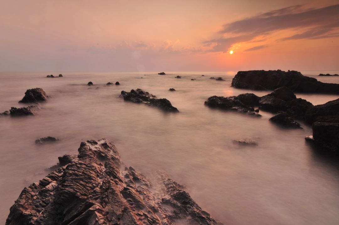 Serene Sunset Over Rocky Seacoast with Gentle Waves - Free Images, Stock Photos and Pictures on Pikwizard.com