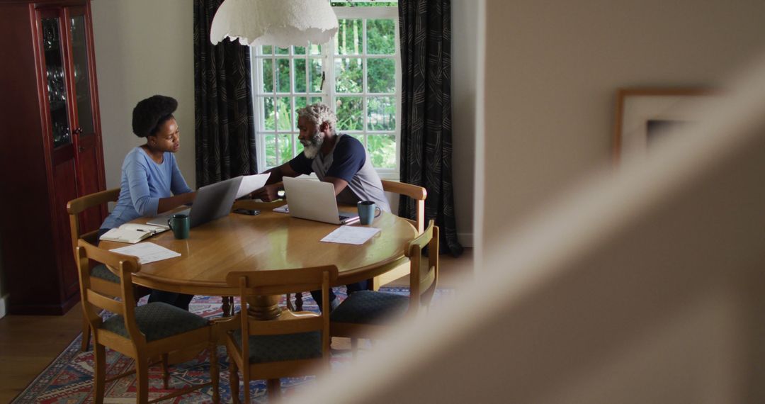 African american couple sitting at dining table using laptops paying bills - Free Images, Stock Photos and Pictures on Pikwizard.com