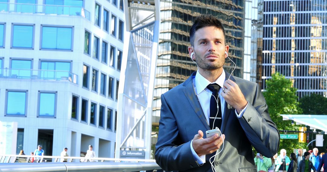 Confident Businessman Using Earphones and Smartphone in City - Free Images, Stock Photos and Pictures on Pikwizard.com