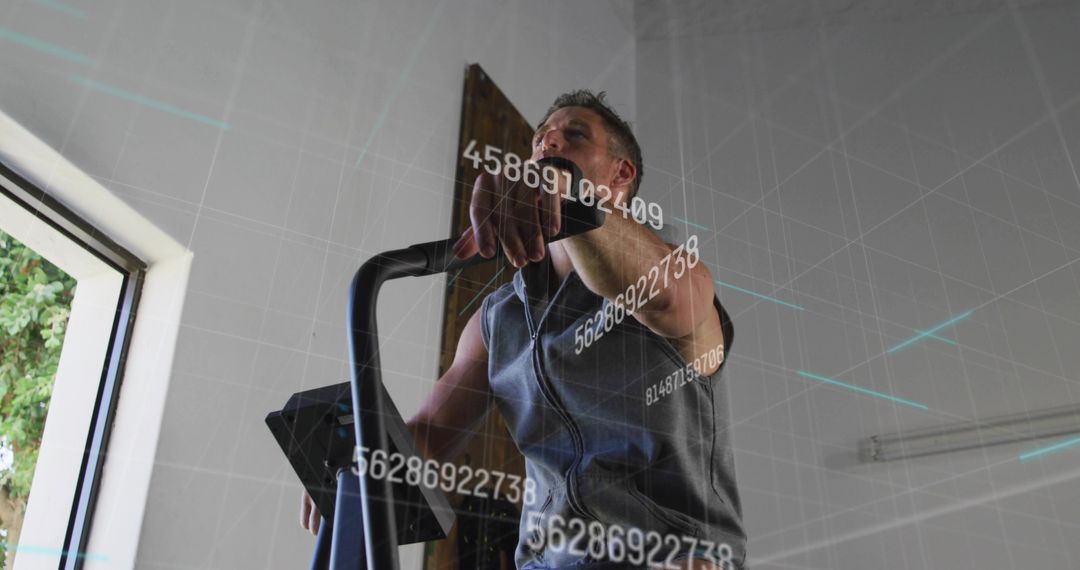 Man Exercising on Elliptical Wearing Earbuds and Fitness Tracker