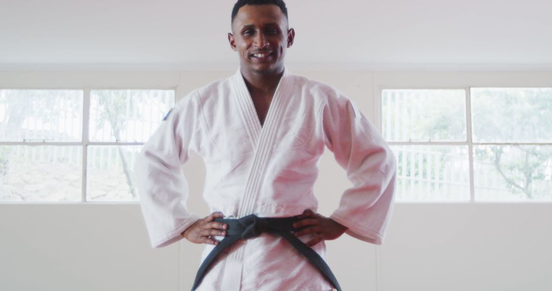 Smiling Martial Artist in White Gi with Black Belt Standing Confidently - Free Images, Stock Photos and Pictures on Pikwizard.com