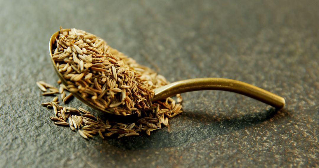 Gold Spoon Filled with Aromatic Cumin Seeds on Stone Surface - Free Images, Stock Photos and Pictures on Pikwizard.com