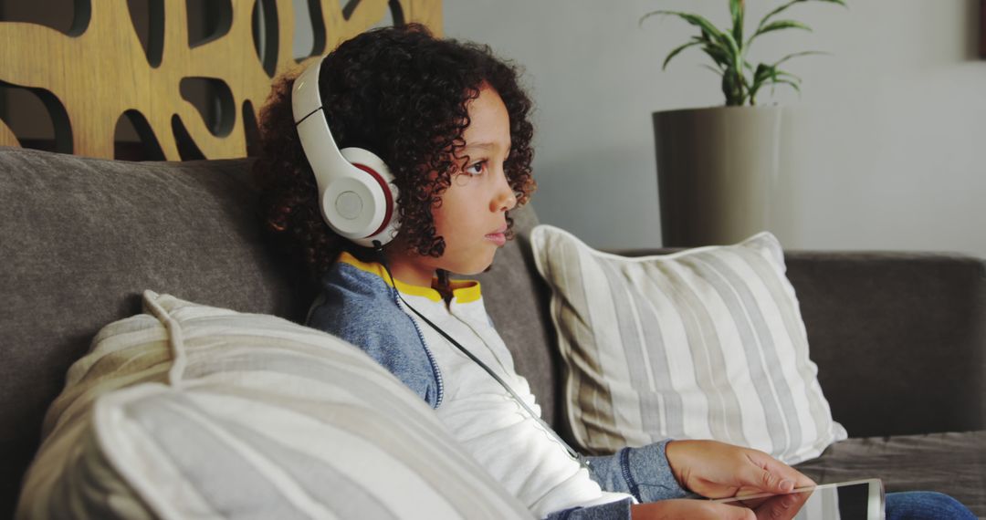 Young Child Listening to Music with Headphones on Sofa - Free Images, Stock Photos and Pictures on Pikwizard.com