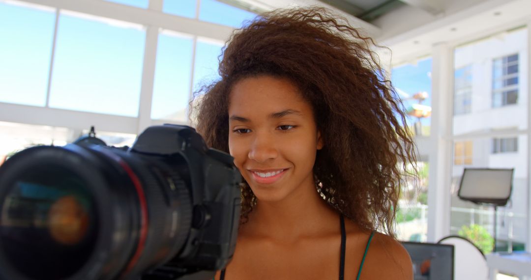 Woman with Curly Hair Smiling at Camera in Bright Studio - Free Images, Stock Photos and Pictures on Pikwizard.com