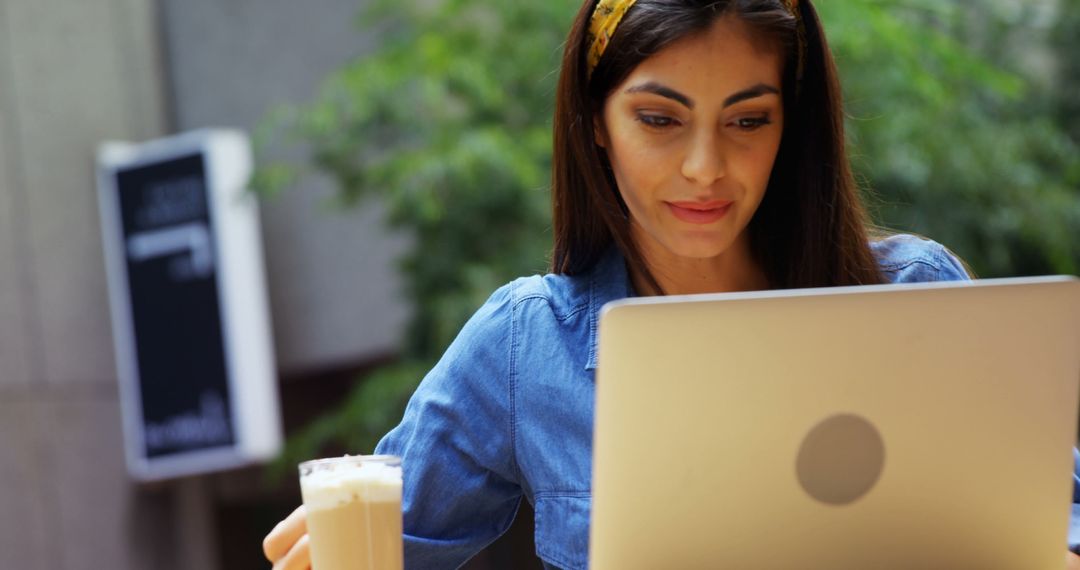 Young Woman Working on Laptop Outdoors Holding Iced Coffee - Free Images, Stock Photos and Pictures on Pikwizard.com