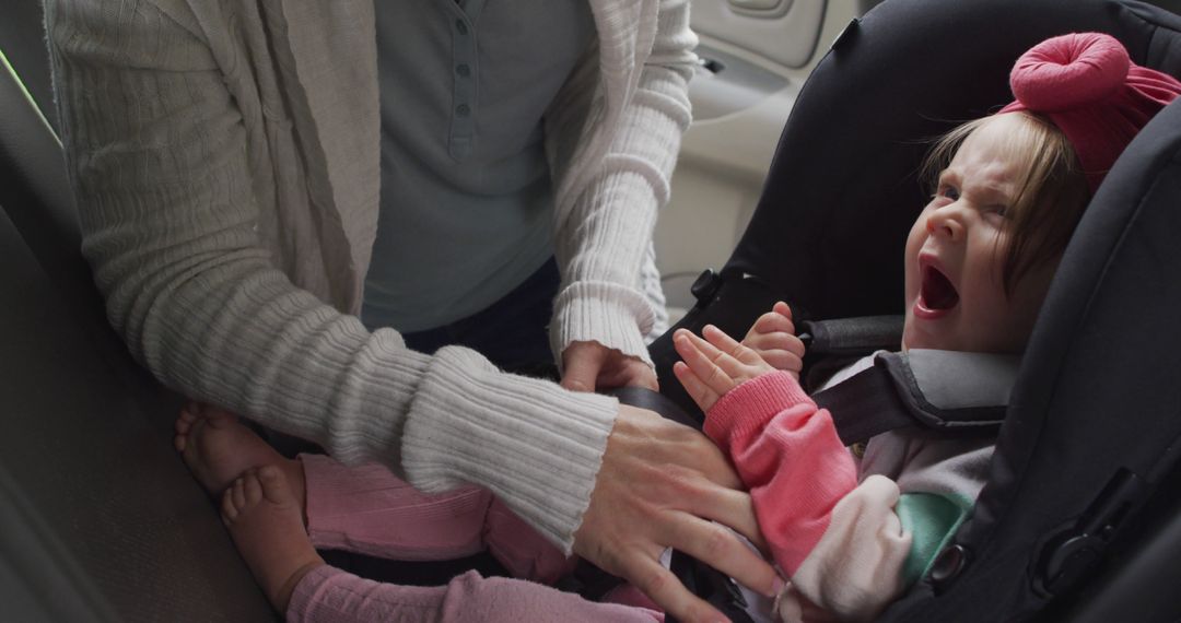 Mother fastening crying baby in car seat - Free Images, Stock Photos and Pictures on Pikwizard.com