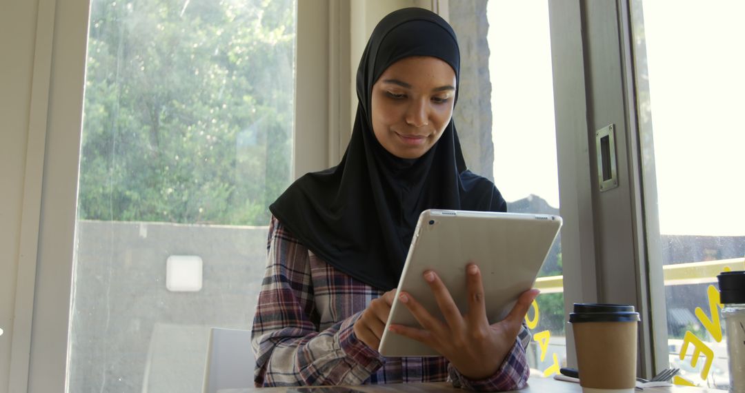 Young Muslim Woman Using Tablet in Modern Cafe - Free Images, Stock Photos and Pictures on Pikwizard.com