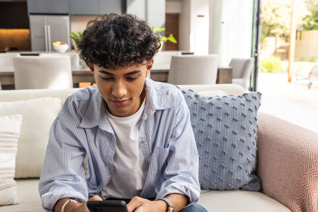 Young Man Relaxing in Modern Living Room Using Smartphone